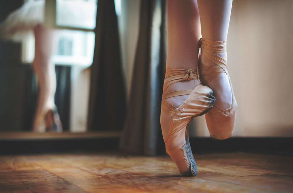 A close up image of a ballerina's shoes on pointe